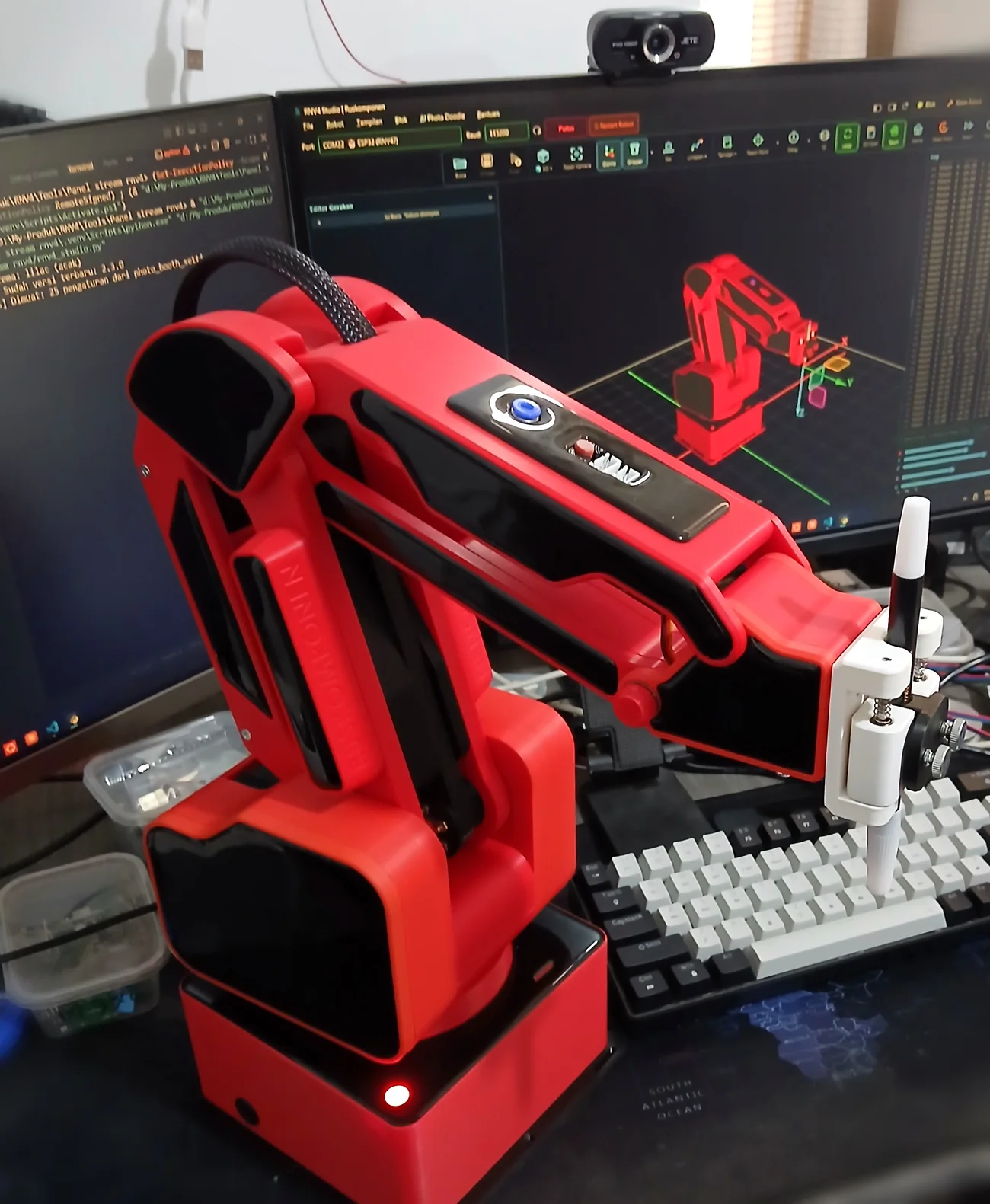 Robot RNV4 merah di meja dengan RNV4 Studio terbuka di monitor
