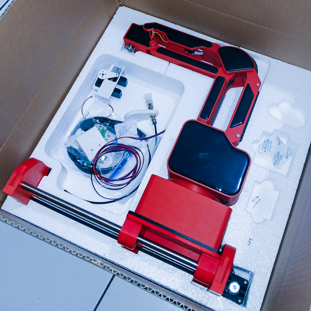 Lapisan bawah kemasan RNV4H2: rangka robot merah terkunci di styrofoam bersama kabel, gripper, dan silica gel
